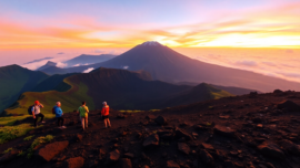 Hikers viewing Mount Rinjani at sunrise from the crater rim with vibrant sky and lush landscape